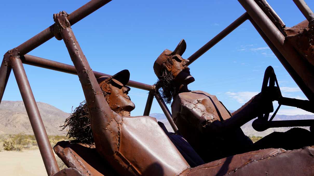 Statue of two people riding in rock climbing Jeep