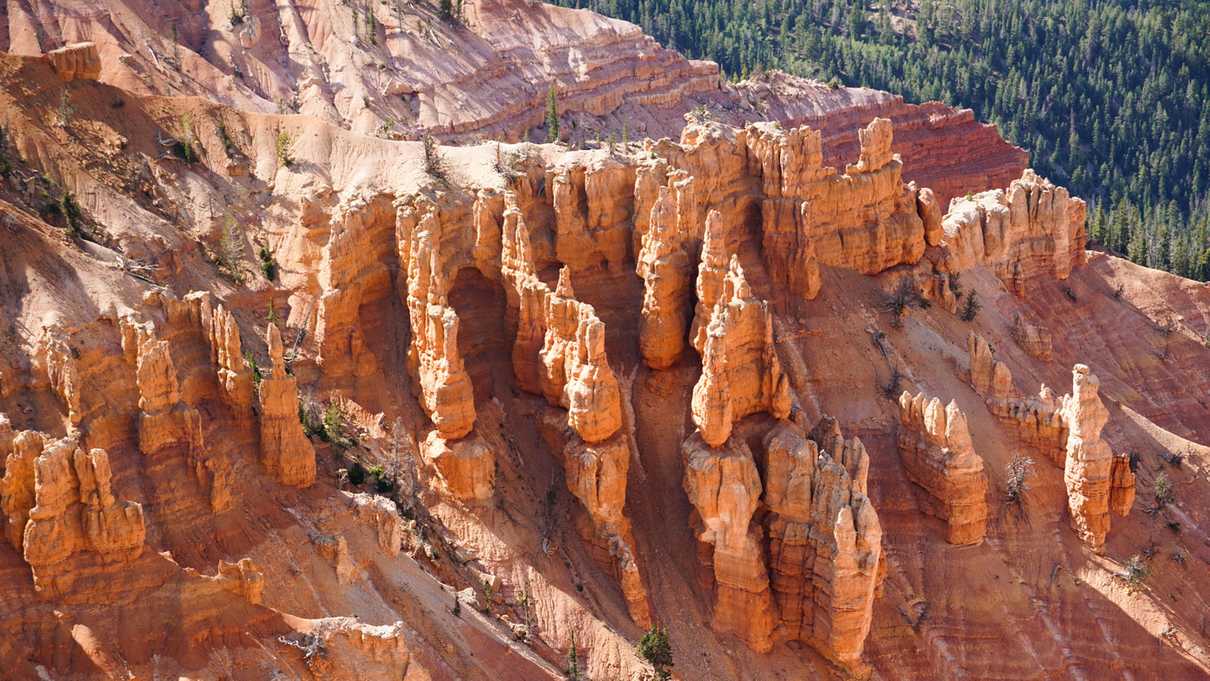 Red rock formations stand upward from a steep canyon wall