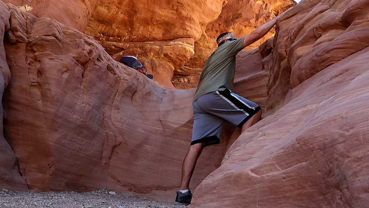 Man reaching to climb up short canyon wall
