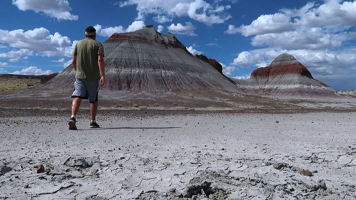 Man walking towards striped hills