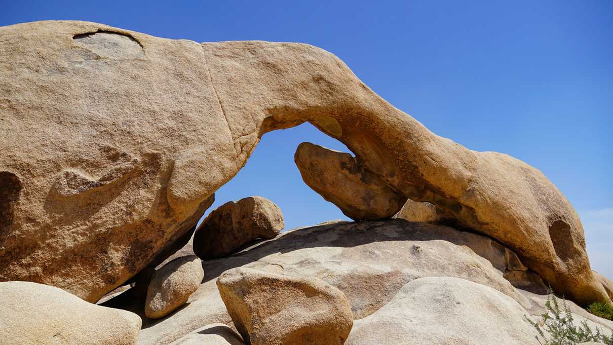 Curved rock arch spanning over numerous boulders