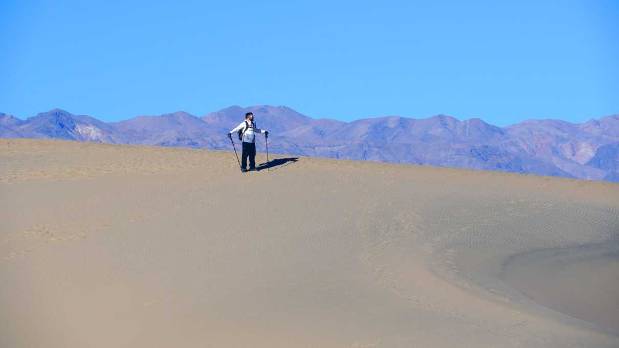 Hiker stands along ridge of sand dune