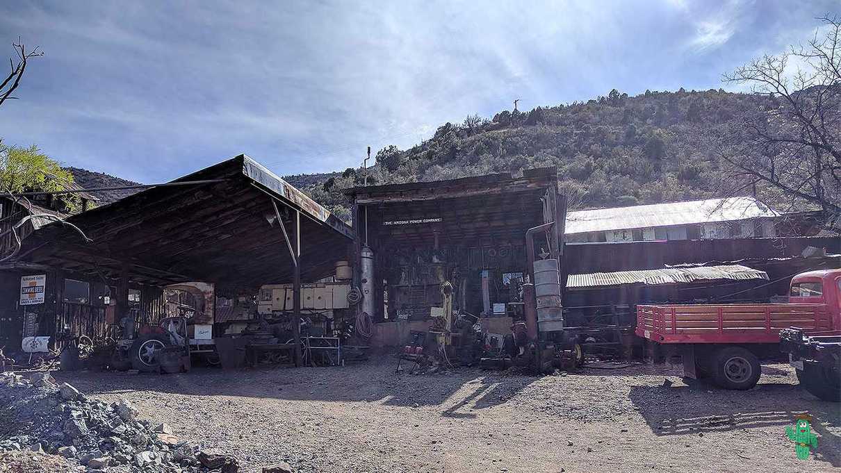 Old wooden buildings with antique vehicles and gas engine