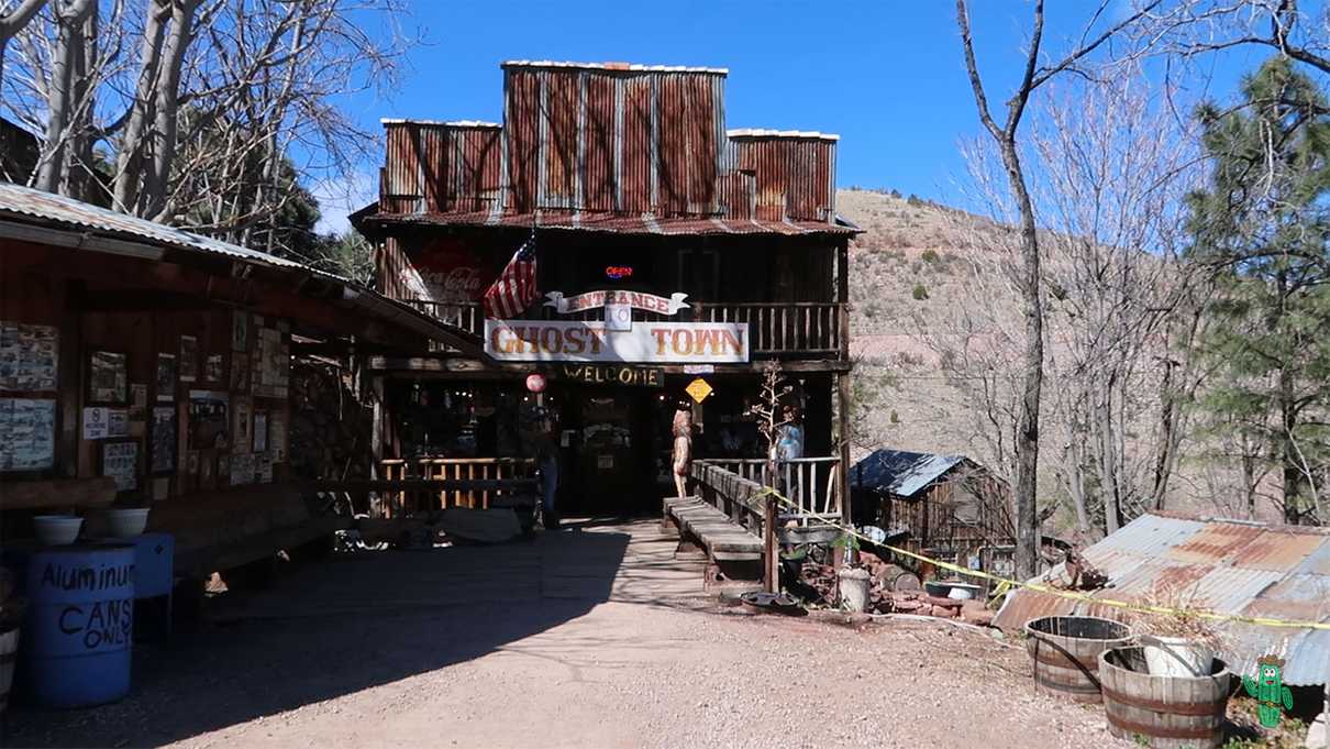 Old wooden building with rusty rooftop and signs advertising entrance to ghost town