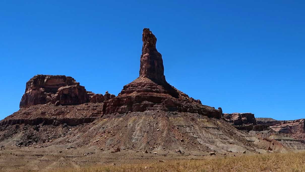 Narrow pinnacle of rock standing against blue sky