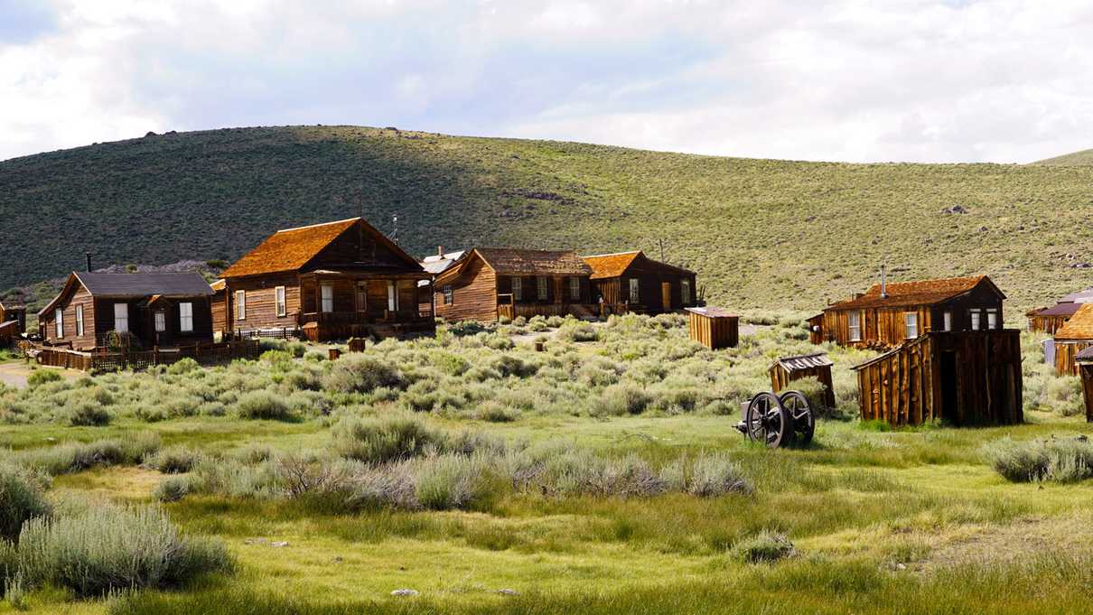 Wooden buildings and miining equipment dot grassy hillside