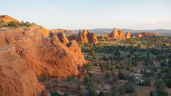 Tall narrow red sandstone rocks stand amid a landscape of greenery