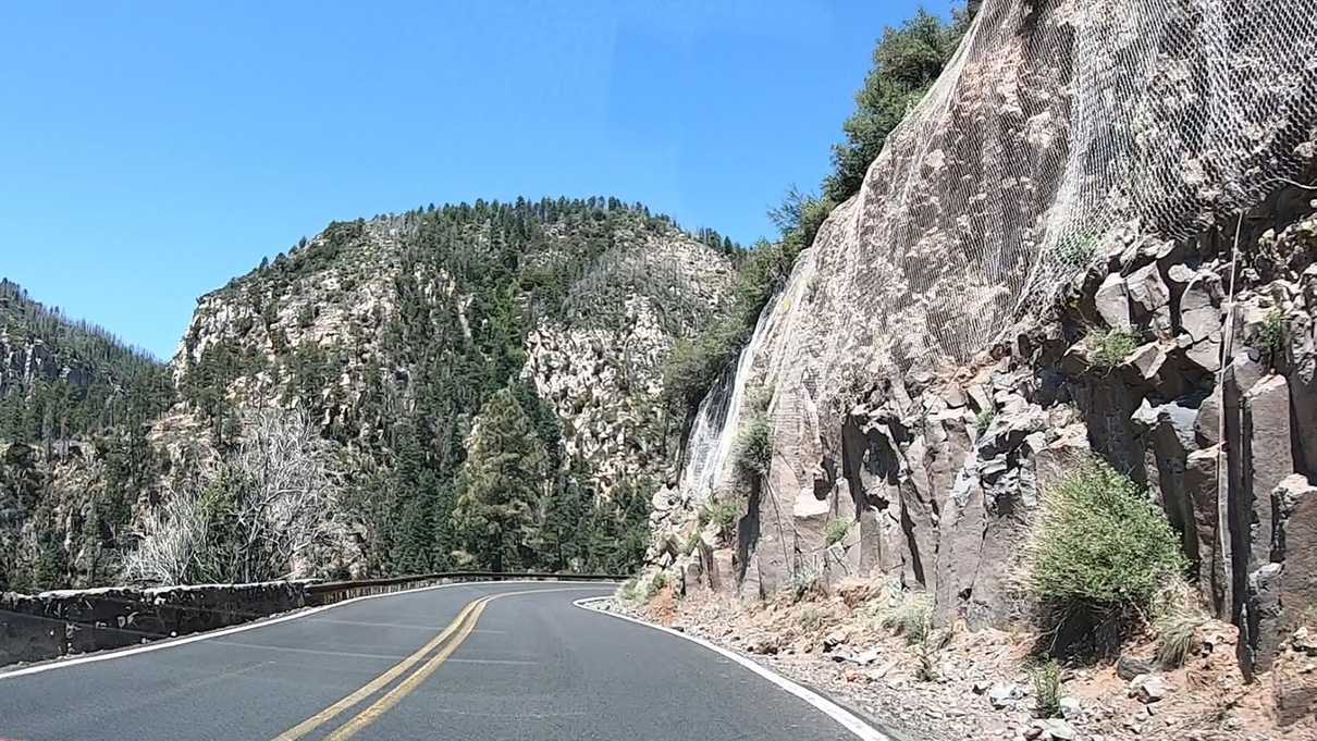 Vertical wall of rock on right side of road descending down