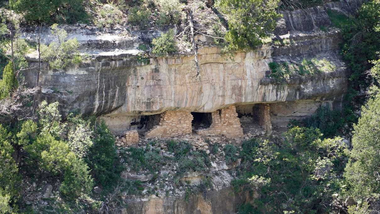 Remains of rock-walled cliff dwellings built into the side of canyon wall