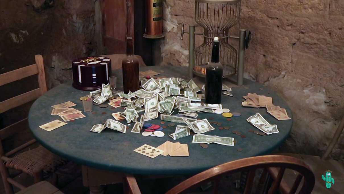 Pile of dollar bills and playing cards on top of an old card table
