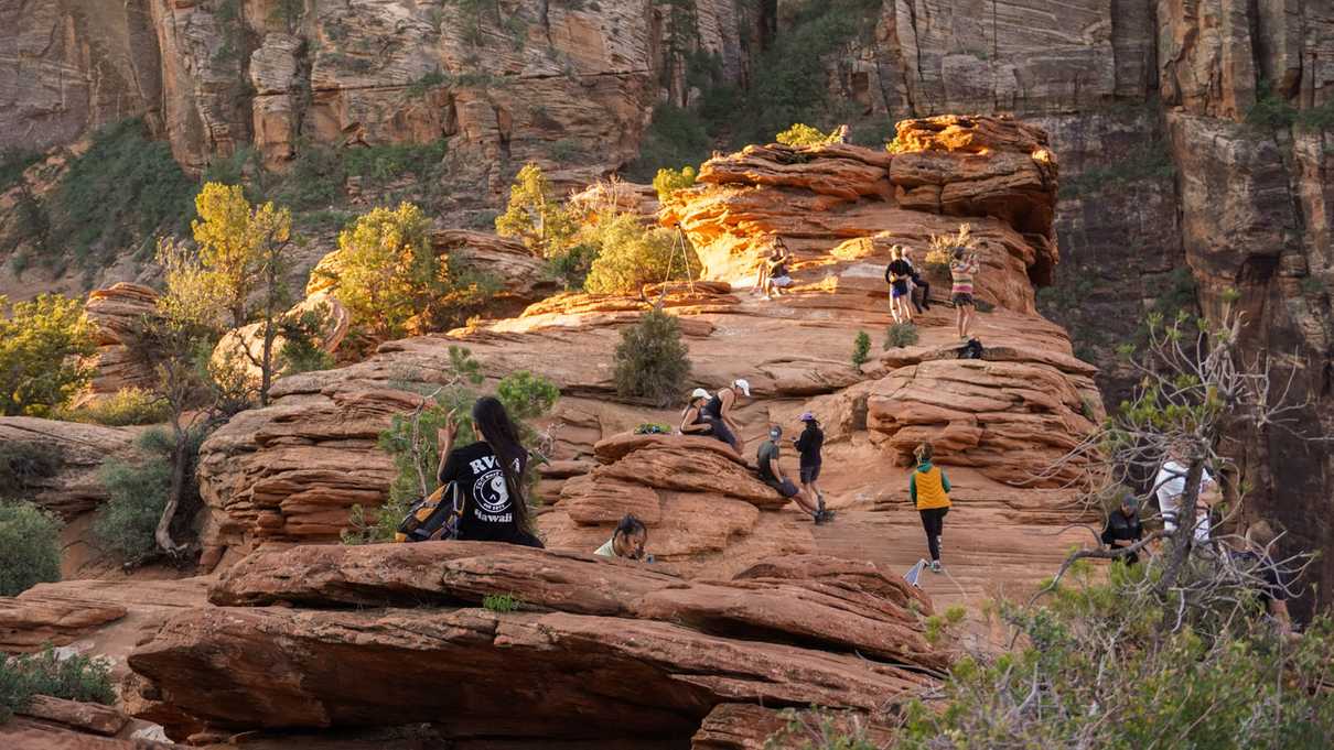 Many figures stand around red rock overlook