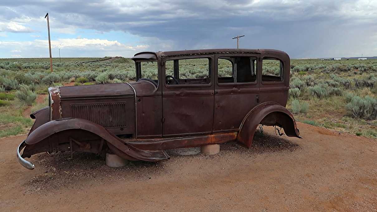 Rusty 1932 Studebaker with telephone poles and interstate in background