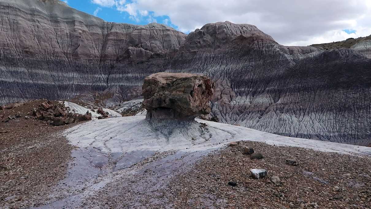 Small pillar of rock in foreground and striped wrinkled hills in background