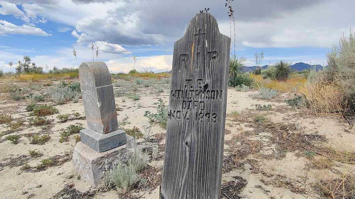 Aged wooden and stone grave markers in barren landscape
